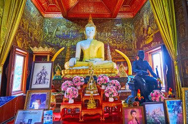 CHIANG MAI, THAILAND - MAY 3, 2019: The white teak Buddha altar in shrine-library of Wat Buppharam with gilt reliefs on walls in background, Chiang Mai