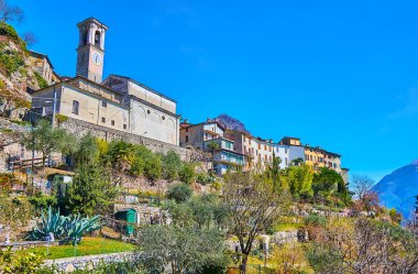 The tall clocktower of medieval San Martino Church dominates the skyline of Castello mountain settlement, Valsolda, Lombardy, Italy