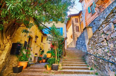 The medieval houses and green plants in pots at the long stone staircase in old Gandria, Ticino, Switzerland