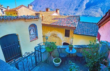 The curved narrow village street with colored houses against the mountains and Lake Lugano, Gandria, Ticino, Switzerland