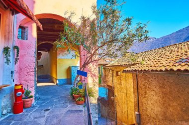 The narrow stone alley and historic living houses with arched passes in Gandria, Ticino, Switzerland