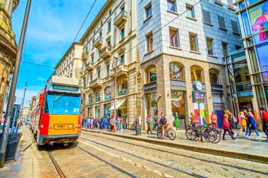MILAN, ITALY - APRIL 11, 2022: The yellow tram rides along Via Torino street, one of the busiest in central district, on April 11 in Milan, Italy