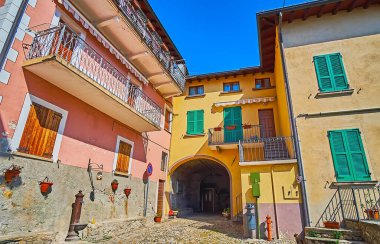 Albogasio, Valsolda, İtalya 'daki Piazza Calderoni' de kemerli geçitleri ve renkli duvarları olan klasik yaşam evleri.