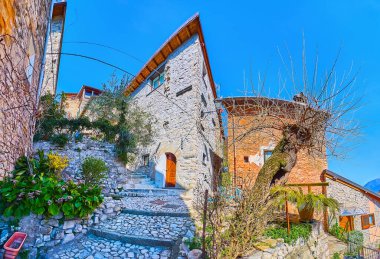 Eski tepe sokağının manzarası kıvrımlı merdivenler, antika taş evler, çiçek yatakları ve yeşil bitkiler, Albogasio, Valsolda, İtalya