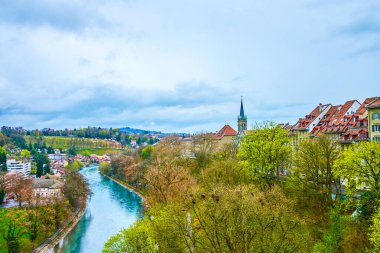 İsviçre, Bern 'de yemyeşil Aare nehrinin yemyeşil parkları ve yürüyen yürüyüşleriyle
