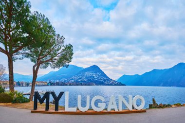 LUGANO, SWitzERLAND - 14 Mart 2022 'de Lugano Gölü' nün yayan seti üzerinde 14 Mart 'ta Lugano' daki Monte Bre 'ye karşı siyah beyaz MyLugano tabelası