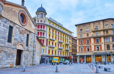 LUGANO, SWitzERLAND - 14 Mart 2022: Santa Maria degli Angeli Kilisesi 'nin ortaçağ taş cepheli Piazza Bernardino Luini, klasik konak evleri, oteller ve mağazalar, Lugano, İsviçre