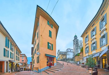 Eski kasabada Via Cattedrale ve Via Borghetto caddelerinin köşesinde dar cepheli eski ev. San Lorenzo Katedrali 'nin küçük dükkanları ve çan kulesi, Lugano, İsviçre