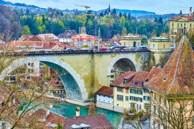 Arched Nydeggbrucke Köprüsü ve İsviçre 'nin Bern kentindeki Aare nehrinin nehir kenarındaki şehir evleri.