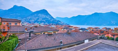 Eski şehrin çatıları, Monte Boglia, Monte Bre, Lugano Gölü ve bulutlu gökyüzü, Lugano, Ticino, İsviçre 'de yer alır.