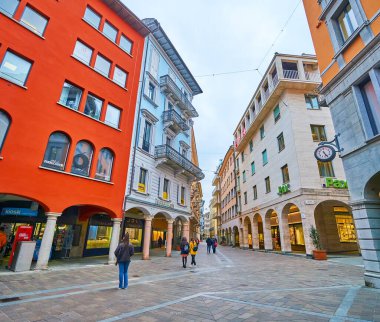 LUGANO, SWitzERLAND - 14 Mart 2022 'de İsviçre' nin Lugano kentinde tarihi evlerin atölyelerinde mağazaları ve marka butikleri olan küçük Piazzetta Emilio Maraini meydanı