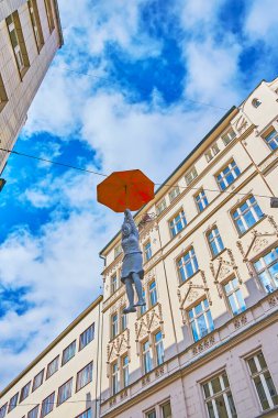 PRAG, CZECHIA - 5 Mart 2022: Michal Trpak 'ın Umbrella Kadını veya Hafif Belirsizlik Kurulumu' nu 5 Mart 'ta Prag' da ev ve mavi gökyüzüne karşı asmak