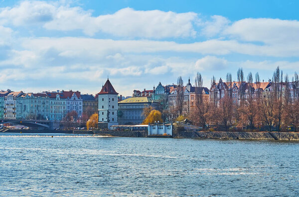 Blue waters of Vltava River with colored townhouses and Malostranska Water Tower in background, Prague, Czech Republic