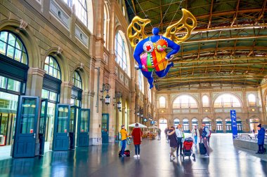 ZURİH, SWitzERLAND - 3 Nisan 2022: Zürih Hauptbahnhof 'un renkli L' ange koruyucu heykeli ile ana salonu, 3 Nisan 'da İsviçre' nin Zürih kentinde Niki de Saint Phalle