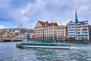 ZURİH, SWitzERLAND - 3 Nisan 2022: Modern kanal teknesi şehrin orta kesimindeki Limmat Nehri üzerinde 3 Nisan 'da İsviçre' nin Zürih kentinde denize açılır.