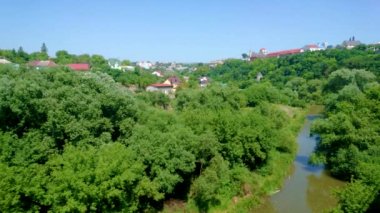 Resimli Smotrych Nehri kanyonu yemyeşil orman, kıvrımlı nehir ve arka planda Kamianets-Podilskyi binaları, Ukrayna