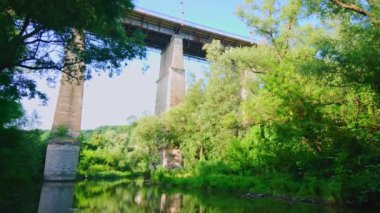 Smotrych Nehri kanyonu boyunca uzanan yüksek beton köprü yemyeşil orman, Kamianets-Podilskyi, Ukrayna boyunca görülür.