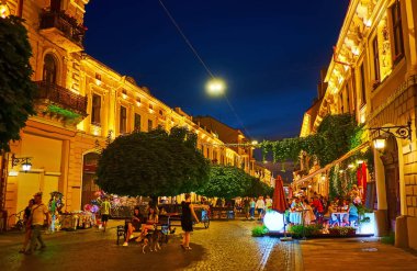 CHERNIVTSI, UKRAINE - 16 Temmuz 2021: Kobylyanska Caddesi, açık hava yemekleri ve parlak akşam ışıkları altında turist restoranları, 16 Temmuz 'da Chernivtsi' de