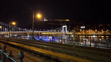 Macaristan 'ın Budapeşte şehrinin Tuna Nehri' nin arkasındaki tepenin üstünde Elisabeth Köprüsü ve Buda Kalesi 'nin aydınlatıldığı akşam manzarası