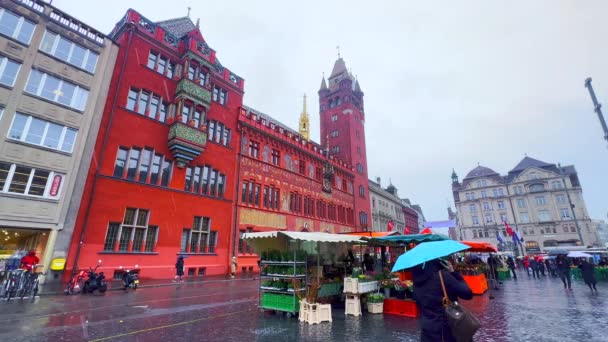 スイスのバーゼル マーケット広場 にあるシティマーケットのフードストアの背後にあるバスラー ラサウス ルートウス タウンホール の豊かな装飾された赤い歴史的建物 — ストック動画