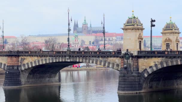 ヴルタヴァ川の景色 歴史的な石は バックグラウンドで近代的なトラムとセントヴィタス大聖堂に乗ってレギオン橋をアーチしました プラハ チェコ共和国 — ストック動画