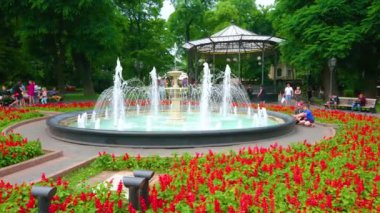 ODESA, UKRAINE - 18 Haziran 2021: Manzaralı çeşmeli Şehir Bahçesi, parlak Salvia çiçek yatakları, yemyeşil ağaçlar ve arka plandaki yazlık ev 18 Haziran 'da Odesa' da