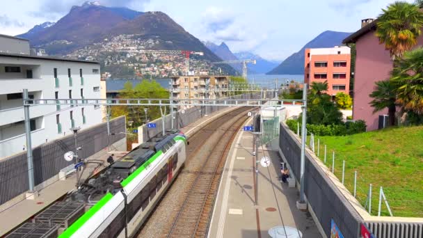客运列车停靠在卢加诺 帕拉迪索火车站 背景是卢加诺湖 布雷山和波格利亚山 瑞士提契诺 — 图库视频影像