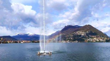 Lugano Körfezi 'ndeki Getto d' Acqua 'nın (Su Jeti, Paradiso Su Jeti) arkasındaki manzaralı Monte Bre' de, Lugano Gölü 'nün dibinde parlak bir gökkuşağı, Lugano, Ticino, İsviçre