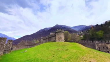 Montebello Kalesi dış koğuşunda, dağ yamacında yer alan, büyük taş duvarları gözlemleyen, vadide ve Alp manzaralı Bellinzona, Ticino, İsviçre