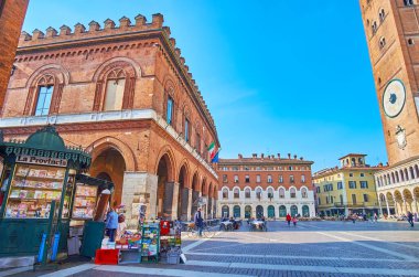 CREMONA, ITALY - 6 Nisan 2022: Piazza del Comune 'un mimari topluluğu ortaçağ belediye binası, Cremona Katedrali' nin çan kulesi ve ön planda klasik gazete büfesi, Lombardy, İtalya