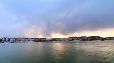 Tuna Nehri üzerinde ve Macaristan 'ın Budapeşte kentinin tarihi mahallelerinde günbatımı gökyüzünde alçak fırtınalı bulutların yer aldığı zaman panoraması