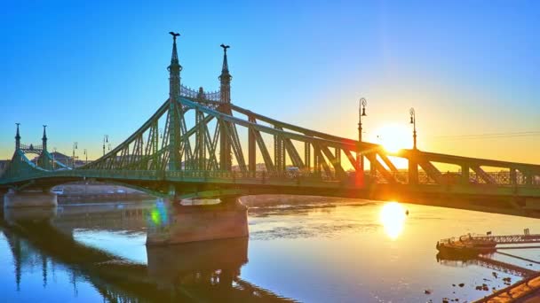 ハンガリー ブダペスト ブダペストの日の出にダヌーブ川の表面とペストのエンバンクに反映されたリバティ橋のタイムラプスパノラマ — ストック動画