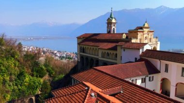 Madonna del Sasso Sığınağı 'nın kırmızı kiremit çatısı ve Santa Maria Assunta Kilisesi' nin çan kulesi Maggiore Gölü, Orselina, İsviçre