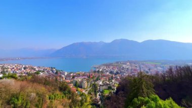 Lepontine Alpleri manzarası, Maggiore Gölü 'nün parlak mavi yüzeyi, Locarno' nun çatıları ve Orselina, Ticino, İsviçre 'den dağ ormanları.