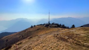 Cimetta Dağı 'nın zirvesinden akşam manzarası kuru sarı yamaçlar, akşam güneşi, sisli Alpler ve Maggiore Gölü, sisle kaplı Ticino, İsviçre