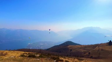 Sisli gökyüzünde uçan bir çok uçan planör uçağının olduğu pitoresk dağ manzarası, Cimetta Dağı, Ticino, İsviçre