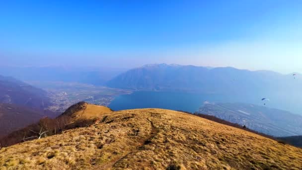朦胧的Lepontine阿尔卑斯山全景 轻雾中的Maggiore湖 以及在瑞士提契诺州Cimetta山上空飞行的滑翔机 — 图库视频影像