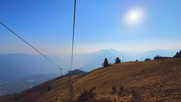 在瑞士提契诺的Cimetta山顶上 你可以看到雾蒙蒙的阿尔卑斯山轮廓 Maggiore湖和滑翔机 享受坐轮椅旅行 — 图库视频影像