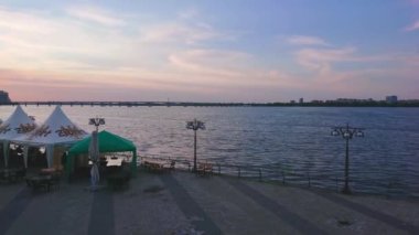 DNIPRO, UKRAINE - 23 Ağustos 2021: Günbatımında Dinyeper Nehri 'nin dalgalanan panoraması, Sicheslav Embankment ve turist zevk tekneleri ile birlikte, 23 Ağustos' ta Dinyeper 'de