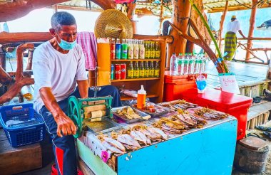 PHANG NGA, THAILAND - 28 Nisan 2019: Yaşlı tüccar, Ko Panyi yüzen Müslüman köyü Phang Nga, Tayland 'da küçük bir pazarda el yapımı kurutulmuş mürekkep balığı öğütücüsü işletiyor