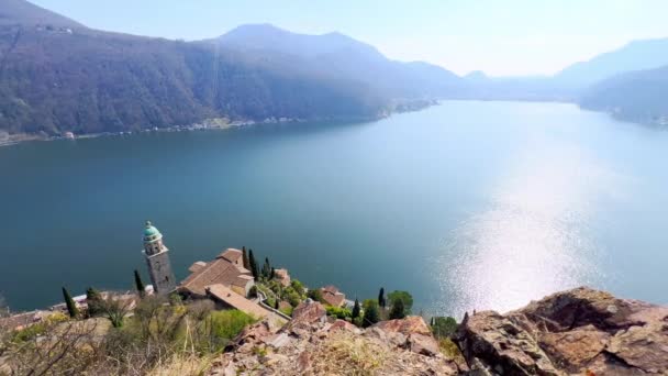 明亮的蓝湖卢加诺 四周环绕着阿尔卑斯山 环绕着瑞士莫科特Arbostora山山坡上的Santa Maria Del Sasso教堂 — 图库视频影像