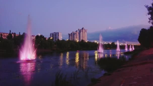 ウクライナ キエフ バックグラウンドの近代的な建物の景色を望むローザンビフスキー運河の噴水をブリッジリーで照らしました — ストック動画