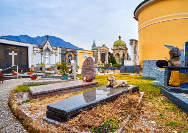 COLLINA D'ORO, SWITZERLAND - MARCH 18,2022: The tombstones with sculptures in monumental cemetery of Sant'Abbondio, on March 18 in Collina d'Oro, Switzerland clipart