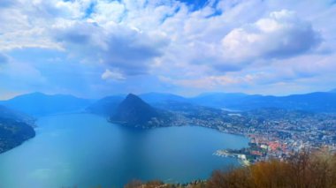 Monte San Salvatore ve Lugano Gölü üzerinde Monte Bre, Ticino, İsviçre 'nin zirvesinden mavi gökyüzünde hızla akan tüylü bulutların zamanı.