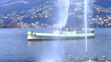Lugano Gölü 'nün panoraması Getto d' Acqua (Lugano Körfezi 'ndeki Su Jeti) çeşmesi, yüzen turist feribotu ve Lugano' nun İsviçre 'nin göl kıyısındaki konutu.