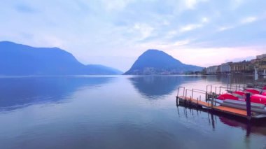 Lugano Gölü 'nün puslu manzarası, Lugano Prealps' in mavi siluetlerini yansıtıyor Monte San Salvatore ve Monte Bre, Lugano, İsviçre