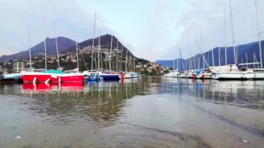 Lugano Gölü 'nün dalgalı yüzeyi Lugano Marina ve Monte Bre, Lugano, Ticino, İsviçre' de demirli tekneler ve yelkenli yatlar manzaralı.