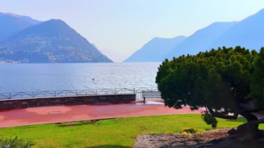 Kozalaklı Riva Paradiso seti panoraması, çiçek açan biberiye, yeşil çimen ve Lugano Gölü ve Monte Bre manzarası, Lugano, İsviçre