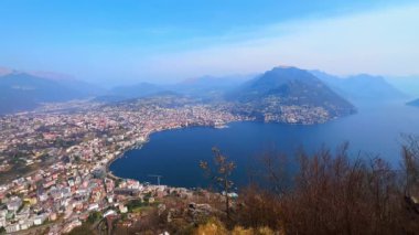 Monte San Salvatore zirvesi Lugano 'nun yaşam bölgeleri, banliyöleri, Lugano Gölü ve İsviçre' deki Ticino Gölü ve Monte Bre ile şehir manzarasını gözlemler.