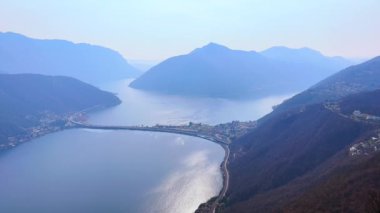 Arka planda Melide Causeway ile Lugano Gölü ve Monte San Giorgio silueti, Monte San Salvatore, Ticino, İsviçre manzarası
